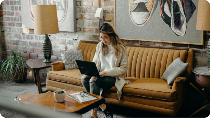 Woman sitting on a couch with a laptop, representing affiliates earning recurring commissions through the WebinarJam partner program.